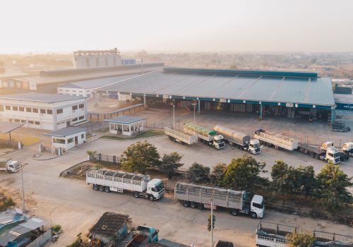 An aerial shot of factory trucks parked near the warehouse at daytime